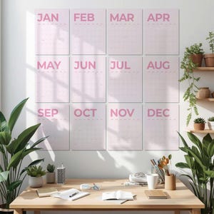 May include: A wall calendar set featuring twelve individual rectangular sheets, each displaying a month from January to December in bold pink lettering. The calendar pages are arranged in a grid of three columns and four rows on a white wall.