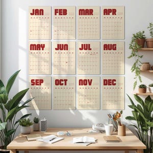 May include: A collection of twelve monthly calendars, each with a cream background and a grid of dates. The month names, in red, are displayed at the top. The calendars are arranged in three rows of four and are mounted on a white wall.