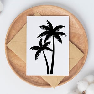 May include: A white card with a black palm tree design, placed on a wooden plate with a brown envelope. The palm tree illustration features two trees with detailed fronds. The background includes white and brown elements.