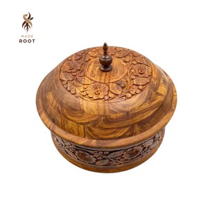 Puede incluir: Un cuenco de madera hecho a mano con tapa, con intrincadas tallas florales. El cuenco es de madera marrón cálido, con un diseño detallado alrededor del borde y en la tapa. La tapa tiene un pequeño pomo decorativo. El logotipo "MADE ROOT" es visible.