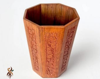 May include: A handcrafted wooden container with an octagonal shape. The container is a warm brown colour and features intricate floral carvings on its sides. The base of the container has the text "MADE ROOT".