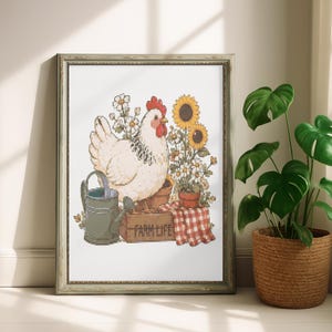 May include: A framed cross-stitch pattern featuring a white chicken standing on a wooden crate labeled FARM LIFE, next to a gray watering can, sunflowers, daisies, and a red and white checkered cloth, all rendered in detailed embroidery stitches.