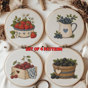 May include: A set of four circular embroidery hoops featuring cross-stitch patterns of fruit: a bowl of strawberries, a pitcher of blueberries, a wooden crate of cherries, and a basket of blackberries. The text SET OF 4 PATTERN is centered.