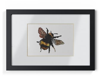 May include: Watercolor painting of a bumblebee with black, yellow, and brown markings. The bee is framed in a black rectangular frame with a white mat. The artwork is a close-up of the insect, showcasing its wings and body details.