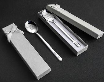 May include: Three silver spoons with custom text, presented in grey gift boxes with ribbon. One spoon reads "Custom Text Here", another "Santa's Favorite Spoon", and the third reads "Your Text". The spoons are on a black surface.