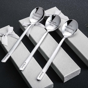 May include: Three silver spoons with engraved text, each in a gift box with a white ribbon. The spoons have the following text: "Santa's Favorite Spoon", "Noah Cake Smash 2026", and "Our Morning Ritual". The spoon handles are engraved with names.