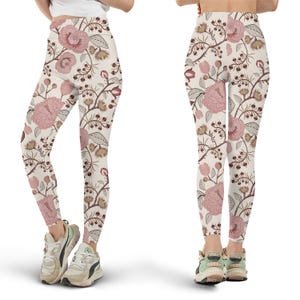May include: Leggings with a floral pattern. The leggings feature a cream-colored background with a repeating design of pink flowers, brown branches, and green leaves. The leggings are shown from the front and back, worn with sneakers.