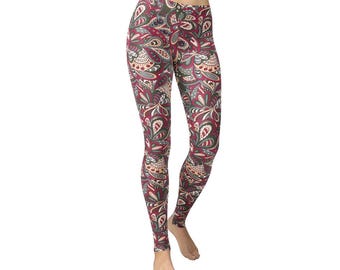 May include: Full-length leggings with a colorful paisley pattern. The leggings feature a burgundy background with a repeating design of white, green, and tan floral and leaf shapes. The leggings are form-fitting and made of a stretchy material.