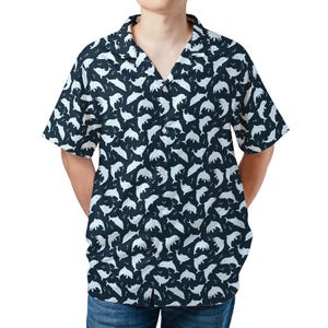 Könnte beinhalten: Marineblaues kurzärmeliges Hemd mit weißem Delfinmuster. Das Hemd hat einen klassischen Kragen und eine Knopfleiste. Das Delfin-Design wiederholt sich über das gesamte Hemd.