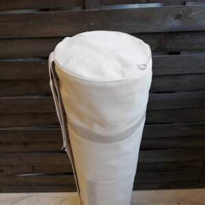 K&ouml;nnte beinhalten: Eine wei&szlig;e Canvas-Yogamatte-Tasche mit Rei&szlig;verschluss und Schultergurt.