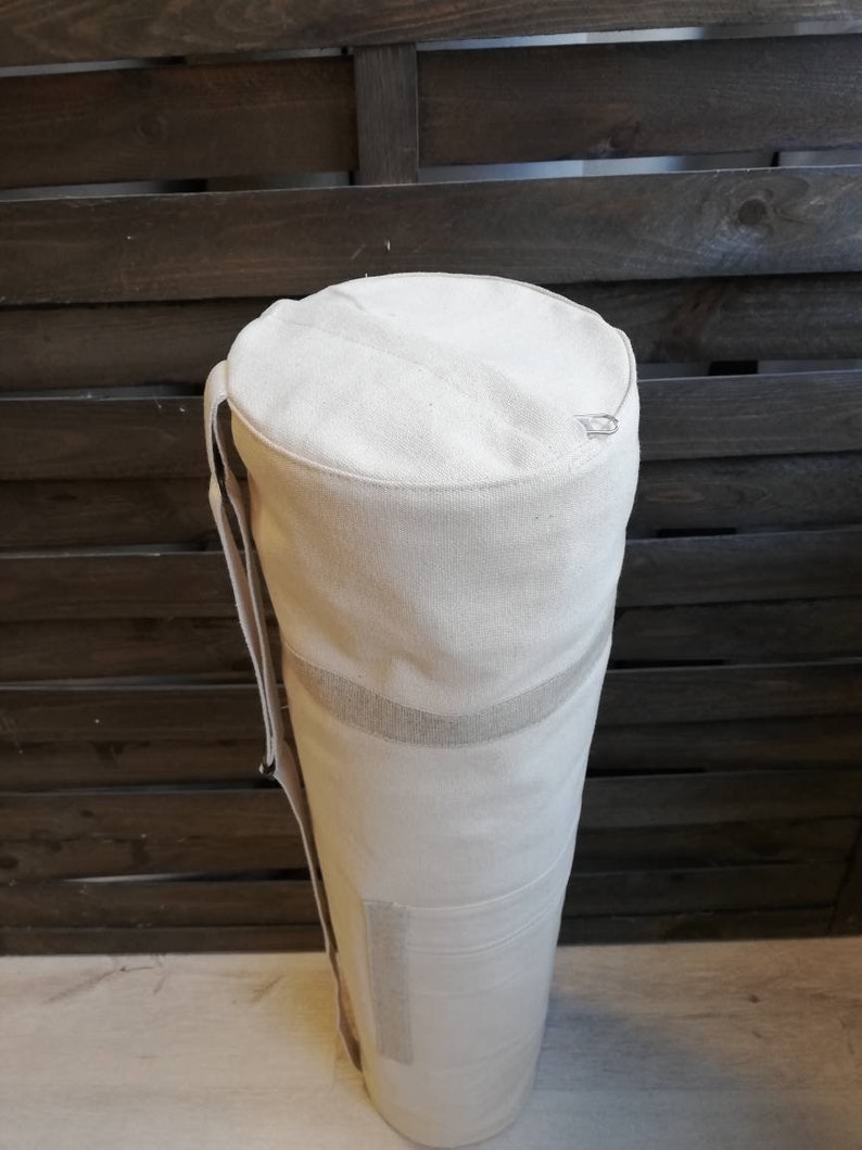 K&ouml;nnte beinhalten: Eine wei&szlig;e Canvas-Yogamatte-Tasche mit Rei&szlig;verschluss und Schultergurt.