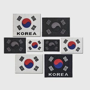 Op de afbeelding: Een verzameling geborduurde patches met de Zuid-Koreaanse vlag. De patches zijn in verschillende maten en oriëntaties, met het rode en blauwe Taegeuk-symbool en de zwarte trigrammen van de vlag.