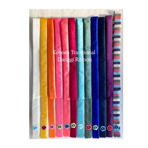 Op de afbeelding: Een verzameling Koreaanse traditionele Danggui-linten in verschillende kleuren, waaronder wit, geel, oranje, roze, rood, blauw en paars. Elk lint is versierd met een kleine bloemversiering. De linten worden verticaal weergegeven.