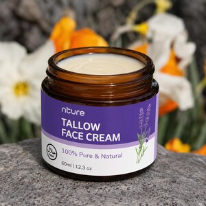 Op de afbeelding: Een pot Tallow Face Cream met een paars etiket. Het etiket toont "nture TALLOW FACE CREAM 100% Pure & Natural" en een Halal-symbool. De pot bevat 60 ml crème en lavendel.