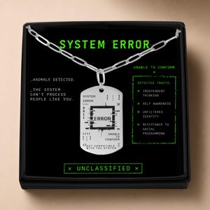 May include: A silver-toned dog tag pendant necklace featuring a black graphic design with the text SYSTEM ERROR, ANOMALY DETECTED, THE SYSTEM CAN'T PROCESS PEOPLE LIKE YOU, UNABLE TO CONFORM, and a list of detected traits including INDEPENDENT THINKING.