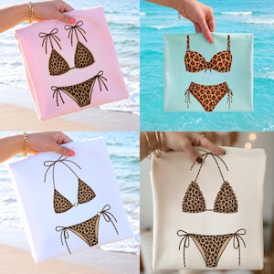 May include: Four images of bikini sets on different colored backgrounds. Each bikini features a leopard print design. The backgrounds are pink, light blue, white, and cream. The bikini tops and bottoms are displayed separately, with tie details.