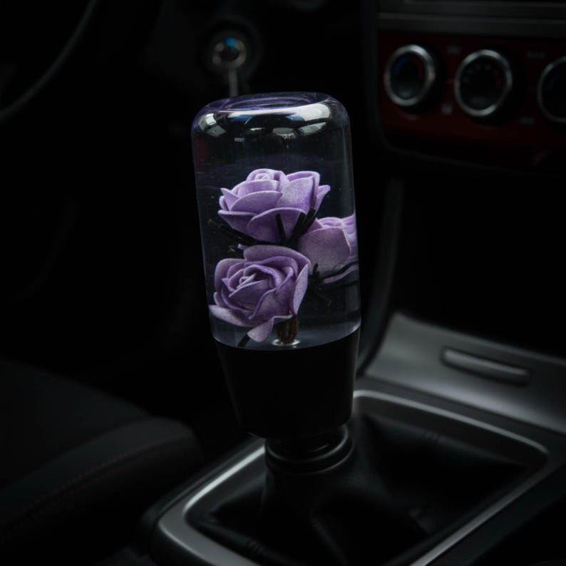 Purple roses weighted shift knob installed in a manual transmission car, clear resin flower shift knob with 3 violet roses on a black base, custom shift knob for 6 speed gear shifter, JDM interior upgrade, perfect for sim racing, iRacing and gaming simulator setups, aesthetic gear knob for car enthusiasts who want a unique manual shift knob.