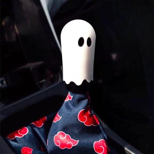 White ghost shift knob mounted on a manual shifter with patterned shift boot in a modified car interior, Halloween themed JDM gear shift knob for 6 speed cars and manual transmission shifter setups, custom weighted shift knob for drift cars, show cars and daily drivers, unique ghost gear knob accessory for tuners and anime fans, also perfect as a sim racing or iRacing gaming simulator shifter knob upgrade for spooky car inspired cockpits.