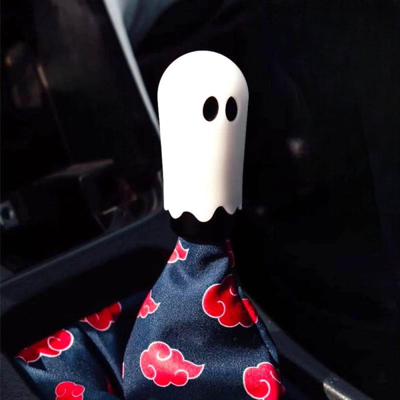 White ghost shift knob mounted on a manual shifter with patterned shift boot in a modified car interior, Halloween themed JDM gear shift knob for 6 speed cars and manual transmission shifter setups, custom weighted shift knob for drift cars, show cars and daily drivers, unique ghost gear knob accessory for tuners and anime fans, also perfect as a sim racing or iRacing gaming simulator shifter knob upgrade for spooky car inspired cockpits.