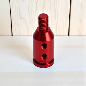 Red aluminum shift knob adapter compatible with non-threaded gear levers and automatic transmissions. Features a durable anodized finish and dual threaded holes for secure mounting. Ideal for JDM cars, BMW-style push-down shifters, or sim racing gear upgrades.