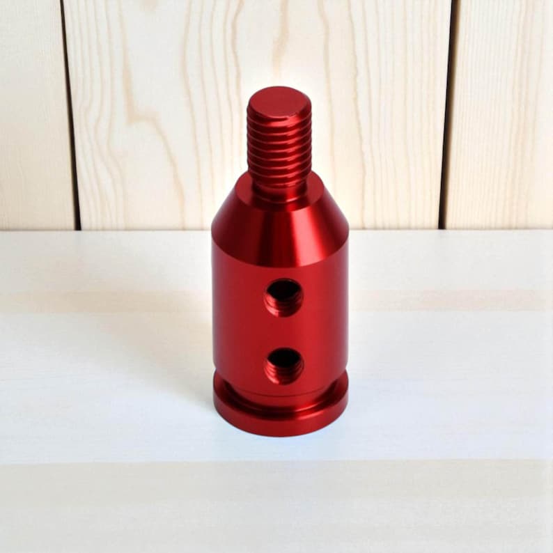 Red aluminum shift knob adapter compatible with non-threaded gear levers and automatic transmissions. Features a durable anodized finish and dual threaded holes for secure mounting. Ideal for JDM cars, BMW-style push-down shifters, or sim racing gear upgrades.