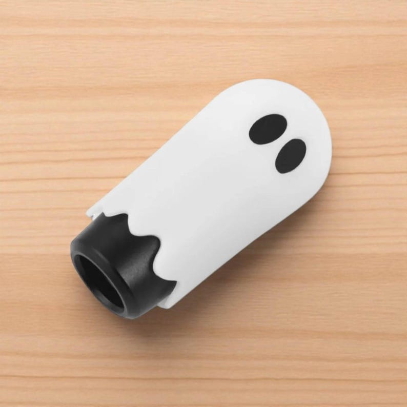 Side view of the ghost shift knob resting on a wooden surface, highlighting its rounded shape and hand-polished resin finish. The playful ghost design makes it stand out in any car interior, from JDM builds to drift and racing setups. This 3.4-inch knob offers smooth handling, enhanced control, and a creative custom touch.