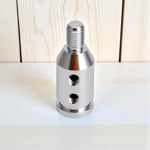 Silver aluminum shift knob adapter for automatic or BMW-style push-down gear shifters. Precision-machined with a metallic finish and multiple thread holes for universal fitment. A durable accessory for installing aftermarket or custom gear shift knobs on non-threaded levers.