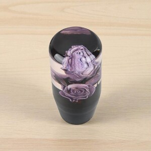 Single purple roses weighted shift knob on light wood background, glossy clear resin top with detailed violet roses and black base, custom manual shift knob for 5 or 6 speed gear shifter, resin shift knob upgrade for JDM interiors, car enthusiasts, sim racing setups and gaming simulator shifter handles.
