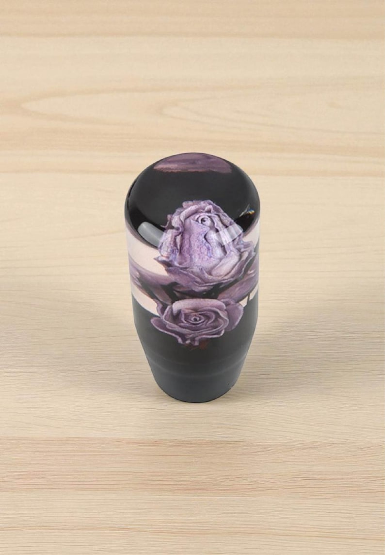 Single purple roses weighted shift knob on light wood background, glossy clear resin top with detailed violet roses and black base, custom manual shift knob for 5 or 6 speed gear shifter, resin shift knob upgrade for JDM interiors, car enthusiasts, sim racing setups and gaming simulator shifter handles.