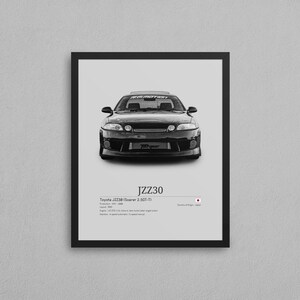 以下が含まれることがあります： 黒いトヨタJZZ30ソアラ2.5GT-Tのモノクロフレームプリント。プリントには車のモデル名、仕様、日本の国旗が含まれています。車は白い背景に配置されています。