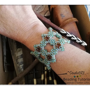 以下が含まれることがあります： ターコイズとブラウンのビーズでできた幾何学模様のブレスレット。ブレスレットは人の手首につけています。画像には「Studio183 Beading Tutorial Copyright Heather Collin」というテキストが含まれています。