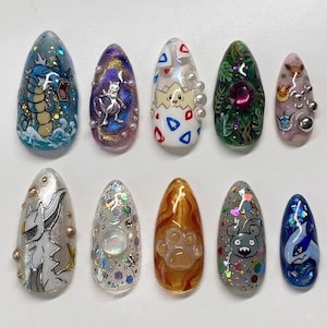 Op de afbeelding: Een set van tien kunstnagels, elk met een uniek ontwerp in levendige kleuren en gedetailleerde kunstwerken. De ontwerpen omvatten een draak, een katachtig wezen en een pootafdruk. De ovaalvormige nagels hebben een glanzende afwerking.