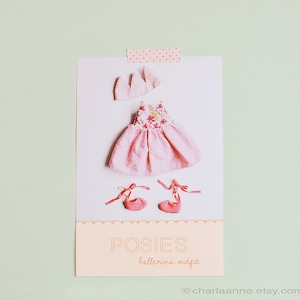 May include: A pink ballerina outfit for a doll, featuring a floral print dress, a crown, and pink ballet shoes. The outfit is displayed on a white background with the text "POSIES' ballerina outfit" and a website address.