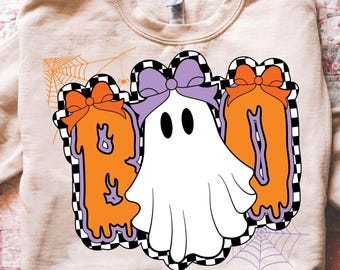 Könnte beinhalten: Beiges Sweatshirt mit einem Halloween-Motiv. Das Design zeigt das Wort "BOO" in Orange, umrandet von einem schwarz-weiß karierten Muster, mit einem weißen Geist und orangefarbenen Schleifen.