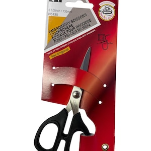 Może przedstawiać: Nożyczki do haftu z czarnymi uchwytami i srebrnymi ostrzami, prezentowane na czerwono-białej karcie produktu. Karta wskazuje, że nożyczki mają 135 mm długości i są wykonane ze stali nierdzewnej o wysokiej zawartości węgla. Opakowanie mówi 'Soft Handle'.