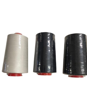 Può includere: Tre rocchetti di filo in fila, ciascuno avvolto in plastica trasparente. I rocchetti sono bianchi, neri e grigio scuro. Ogni rocchetto ha una base rossa.