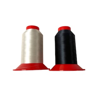 以下が含まれることがあります： 白と黒の2つの糸巻き。どちらも赤いベースと赤い上部が付いています。糸巻きは円筒形で、白い背景に立っています。