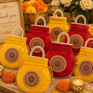 May include: A collection of round drawstring pouches in vibrant yellow and deep red satin fabric. Each pouch features a central circular medallion with intricate gold embroidery and a handle adorned with small white faux pearls.