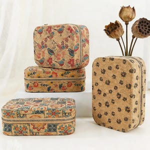 Puede incluir: Una colección de estuches y cajas de viaje de corcho con varios diseños florales y de pájaros. Los estuches tienen cierres de cremallera y son de diferentes tamaños y formas. Una caja presenta un diseño de patchwork.