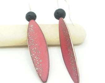 May include: A pair of dangle earrings featuring elongated, leaf-shaped pendants in a vibrant red hue with silver accents. Each earring has a small, round, black bead at the top and a silver hook. The earrings are displayed on a white background.
