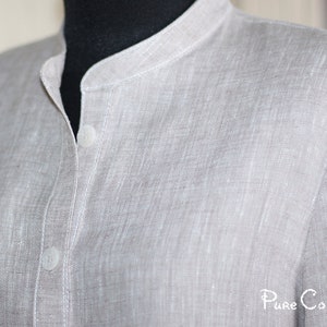 May include: A light gray linen shirt with a mandarin collar and two buttons. The shirt has a textured, woven fabric.