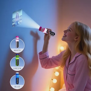 Puede incluir: Una linterna proyector blanca y rosa que proyecta una imagen en una pared. La linterna tiene el texto "Olivia Grace". Se muestran tres linternas adicionales en blanco, verde y azul.