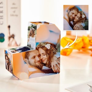 Może przedstawiać: Spersonalizowana kostka fotograficzna z przezroczystego akrylu, prezentująca wiele zdjęć pary. Kostka wyświetla zdjęcia na każdej stronie, z parą uśmiechniętą i obejmującą się. Zdjęcia mają motyw ślubny.