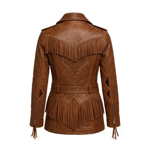 Puede incluir: Chaqueta de cuero marr&oacute;n con flecos en la espalda, hombros y dobladillo. La chaqueta presenta un cintur&oacute;n, tachuelas decorativas y cremalleras en las mangas. Una elegante prenda de vestir exterior de inspiraci&oacute;n occidental.