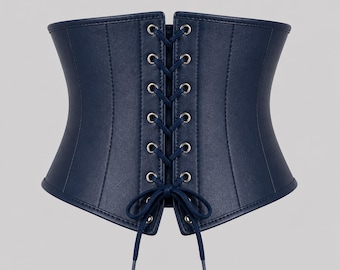 May include: A navy blue corset with a lace-up front. The corset is made of a smooth material and features a structured design. The lacing is secured with silver-toned eyelets. A classic piece of apparel.
