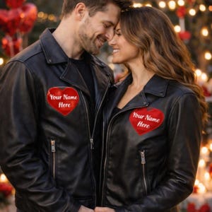 May include: Black leather jackets with red heart patches that read "Your Name Here." The jackets have a classic biker style with notched lapels and zippered pockets. The image shows a couple wearing the jackets.