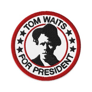 Può includere: Toppa ricamata rossa, bianca e nera con una silhouette di Tom Waits e il testo "Tom Waits for President" in un cerchio.