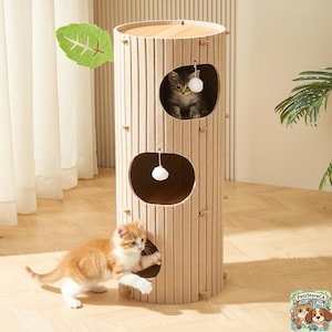 May include: A beige cat tree with two oval openings and a round top. Two kittens are playing in the openings. The cat tree has a leaf decoration and a PetzStoreCA logo.