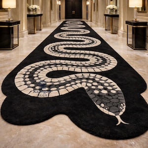 Puede incluir: Una alfombra negra con un diseño de serpiente. La alfombra presenta una serpiente grande y estilizada en tonos grises y beige sobre un fondo negro. El cuerpo de la serpiente serpentea a lo largo de la alfombra, con una cabeza y cola detalladas.
