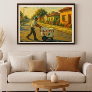 May include: A framed painting depicts a man pushing a cart labeled "PALETAS" down a residential street. The cart has colorful ice pops. The artwork is in warm tones, with houses and trees lining the street. The man wears a light-colored shirt and a blue cap.